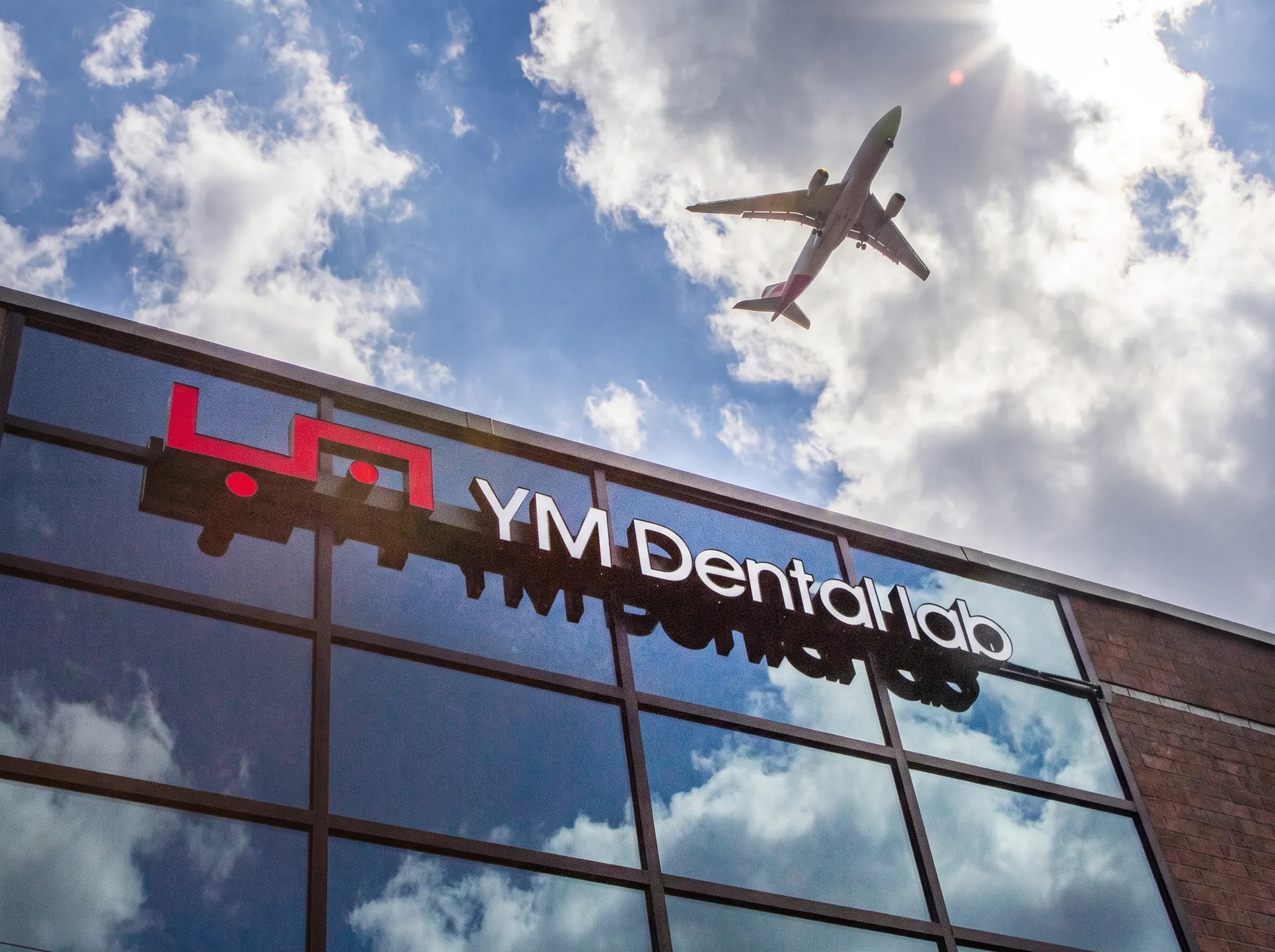 YM Dental Lab exterior with an aircraft passing overhead